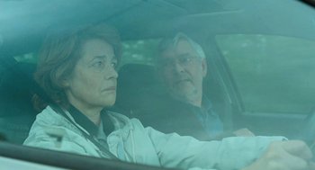 Movie still from “45 Years” (2015), directed by Andrew Haigh – A man and a woman sitting in a car looking out the window; Medium shot, Over the shoulder angle
