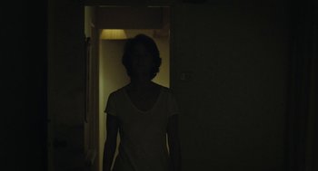 Movie still from “45 Years” (2015), directed by Andrew Haigh – A woman standing in a dark room in front of a door; Medium shot, Low angle