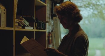 Movie still from “45 Years” (2015), directed by Andrew Haigh – A woman is looking at a piece of paper; Medium shot, Over the shoulder angle