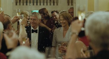 Movie still from “45 Years” (2015), directed by Andrew Haigh – A group of people standing in a room with drinks; Medium shot, Over the shoulder angle