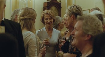 Movie still from “45 Years” (2015), directed by Andrew Haigh – A group of women standing next to each other holding wine glasses; Medium shot, Over the shoulder angle