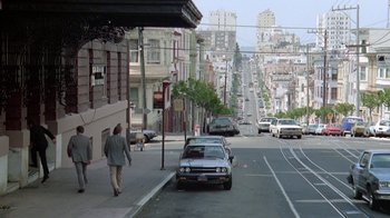 Movie still from “48 Hrs.” (1982), directed by Walter Hill – A man walking down a street next to a car; Extreme Wide shot, High angle