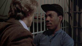 Movie still from “48 Hrs.” (1982), directed by Walter Hill – A man talking to another man in front of a fence; Close Up shot, Over the shoulder angle
