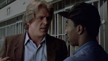 Movie still from “48 Hrs.” (1982), directed by Walter Hill – Two men are talking to each other in front of bars; Close Up shot, Low angle