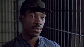 Movie still from “48 Hrs.” (1982), directed by Walter Hill – A man in a cap and a blue shirt; Close Up shot, High angle