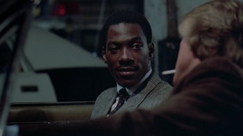 Movie still from “48 Hrs.” (1982), directed by Walter Hill – A man in a suit sitting in front of another man; Close Up shot, Over the shoulder angle