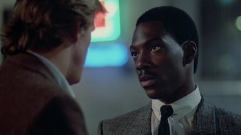 Movie still from “48 Hrs.” (1982), directed by Walter Hill – A man wearing a suit and tie talking to another man wearing a suit and tie; Close Up shot, Over the shoulder angle