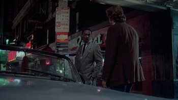 Movie still from “48 Hrs.” (1982), directed by Walter Hill – Two men standing next to each other on the street; Wide shot, Over the shoulder angle
