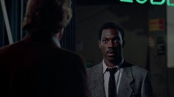 Movie still from “48 Hrs.” (1982), directed by Walter Hill – A man wearing a suit and tie in front of a mirror; Close Up shot, Over the shoulder angle