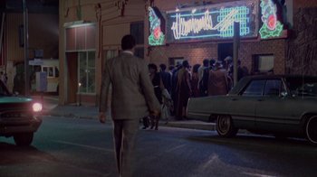 Movie still from “48 Hrs.” (1982), directed by Walter Hill – A man in a suit walking down the street holding hands; Extreme Wide shot, High angle