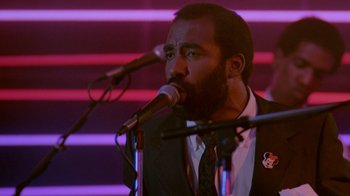 Movie still from “48 Hrs.” (1982), directed by Walter Hill – A man in a suit is singing into a microphone; Close Up shot, Low angle