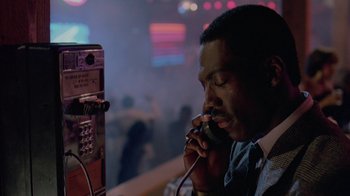 Movie still from “48 Hrs.” (1982), directed by Walter Hill – A man is talking on a phone in front of a phone booth; Close Up shot, Low angle