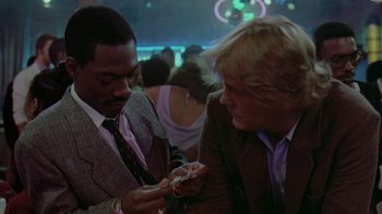 Movie still from “48 Hrs.” (1982), directed by Walter Hill – Two men in suits are looking at a cell phone; Close Up shot, Over the shoulder angle