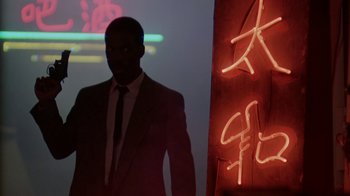 Movie still from “48 Hrs.” (1982), directed by Walter Hill – A man wearing a suit and tie standing in front of a neon sign; Medium shot, Low angle