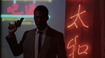 Movie still from “48 Hrs.” (1982), directed by Walter Hill – A man wearing a suit and tie standing in front of a wall; Medium shot, Low angle