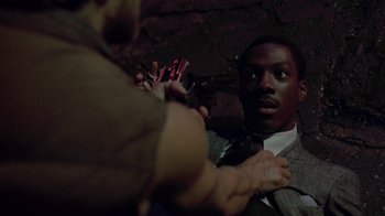 Movie still from “48 Hrs.” (1982), directed by Walter Hill – A man in a suit and tie holding a cell phone; Close Up shot, Over the shoulder angle