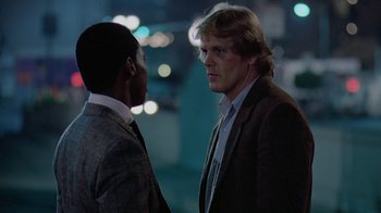 Movie still from “48 Hrs.” (1982), directed by Walter Hill – Two men in business suits facing one another; Medium shot, Over the shoulder angle