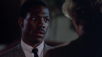 Movie still from “48 Hrs.” (1982), directed by Walter Hill – A man wearing a suit and tie talking to a woman; Close Up shot, Over the shoulder angle