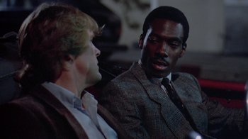 Movie still from “48 Hrs.” (1982), directed by Walter Hill – Two men in suits talking to each other; Close Up shot, Over the shoulder angle