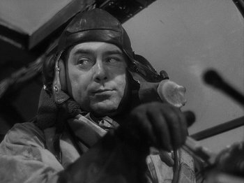 Movie still from “49th Parallel” (1941), directed by Michael Powell – A man wearing a helmet and gloves while holding a gun; Close Up shot, Low angle