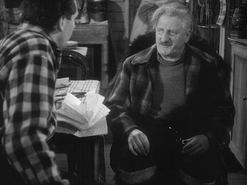 Movie still from “49th Parallel” (1941), directed by Michael Powell – An older man sitting next to a young boy; Medium shot, Over the shoulder angle