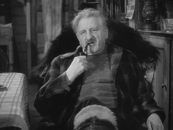 Movie still from “49th Parallel” (1941), directed by Michael Powell – An older man sitting on a chair smoking a pipe; Close Up shot, High angle