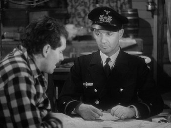 Movie still from “49th Parallel” (1941), directed by Michael Powell – A man in a military uniform talking to another man in a plaid shirt; Medium shot, Over the shoulder angle