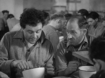 Movie still from “49th Parallel” (1941), directed by Michael Powell – Two men sitting at a table in front of each other; Medium shot, High angle