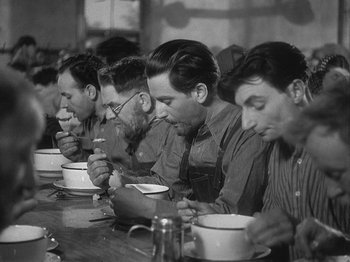 Movie still from “49th Parallel” (1941), directed by Michael Powell – A black and white photo of a group of men eating soup; Medium shot, Low angle