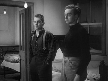Movie still from “49th Parallel” (1941), directed by Michael Powell – Two young men standing next to each other in front of a door; Medium shot, Low angle