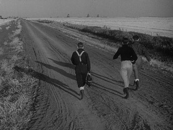 Movie still from “49th Parallel” (1941), directed by Michael Powell – Two men walking down a dirt road in the middle of the day; Wide shot, High angle