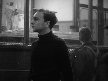 Movie still from “49th Parallel” (1941), directed by Michael Powell – A black and white photo of a man standing in front of a window; Medium shot, Low angle
