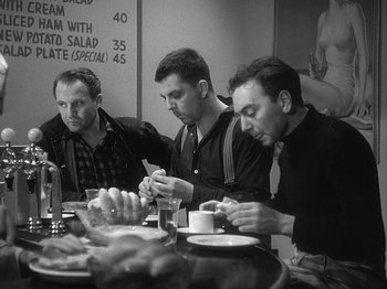 Movie still from “49th Parallel” (1941), directed by Michael Powell – A group of men sitting at a table eating food; Medium shot, Low angle
