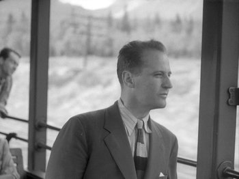 Movie still from “49th Parallel” (1941), directed by Michael Powell – Black and white photograph of a man wearing a suit and tie; Medium shot, Low angle