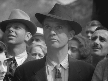Movie still from “49th Parallel” (1941), directed by Michael Powell – Black and white photograph of a man in a suit and hat; Close Up shot, Low angle