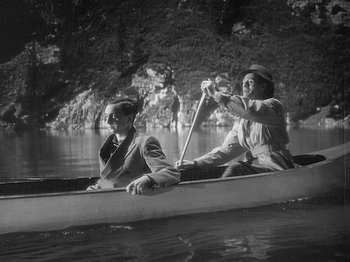 Movie still from “49th Parallel” (1941), directed by Michael Powell – Two people are in a canoe on the water; Wide shot, High angle
