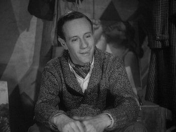 Movie still from “49th Parallel” (1941), directed by Michael Powell – A man sitting on the ground wearing a sweater; Close Up shot, High angle