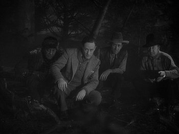 Movie still from “49th Parallel” (1941), directed by Michael Powell – A black and white photo of a group of men sitting on the ground; Medium shot, High angle