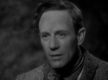 Movie still from “49th Parallel” (1941), directed by Michael Powell – A man in a jacket and a neck tie looking at the camera; Close Up shot, High angle