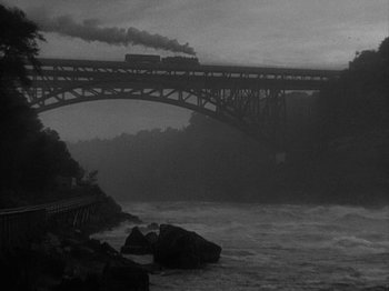 Movie still from “49th Parallel” (1941), directed by Michael Powell – A black and white photo of a train crossing a bridge; Extreme Wide shot, High angle