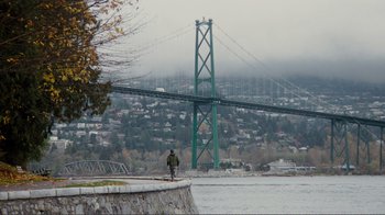 Movie still from “50/50” (2011), directed by Jonathan Levine – A person standing on a wall near a body of water; Extreme Wide shot, High angle