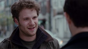 Movie still from “50/50” (2011), directed by Jonathan Levine – A young man smiling while talking to another man in the street; Close Up shot, Over the shoulder angle