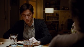 Movie still from “50/50” (2011), directed by Jonathan Levine – A man sitting at a table looking down at a cell phone; Medium shot, Over the shoulder angle