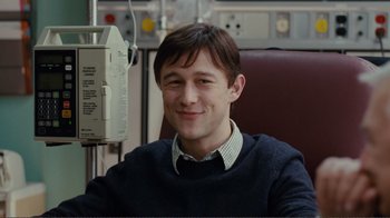 Movie still from “50/50” (2011), directed by Jonathan Levine – A young man sitting in a chair in front of an infusion pump; Medium shot, High angle