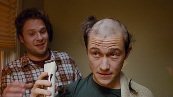 Movie still from “50/50” (2011), directed by Jonathan Levine – A man with a shaved head is holding a hair trimmer while another man looks on; Close Up shot, Over the shoulder angle