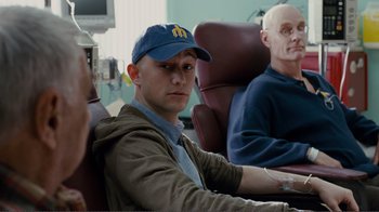 Movie still from “50/50” (2011), directed by Jonathan Levine – A man sitting in front of another man in a chair; Close Up shot, Over the shoulder angle