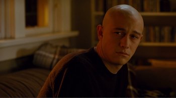 Movie still from “50/50” (2011), directed by Jonathan Levine – A man with a bald head sitting on a couch; Close Up shot, Over the shoulder angle