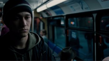 Movie still from “50/50” (2011), directed by Jonathan Levine – A young man riding on a train with a hat on his head; Close Up shot, Over the shoulder angle