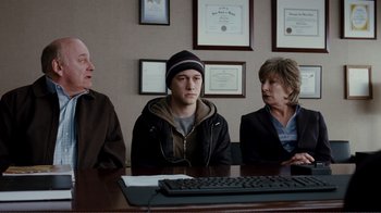 Movie still from “50/50” (2011), directed by Jonathan Levine – Three people sitting at a table with a computer keyboard; Medium shot, Over the shoulder angle