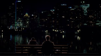 Movie still from “50/50” (2011), directed by Jonathan Levine – Two people sitting on a bench looking out at a city skyline at night; Extreme Wide shot, High angle